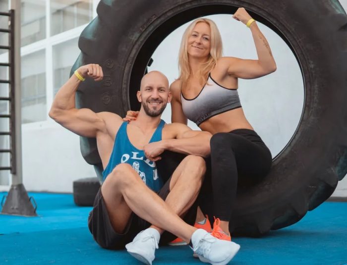 Energetic couple showing strength and fitness at the gym with a large tire.
